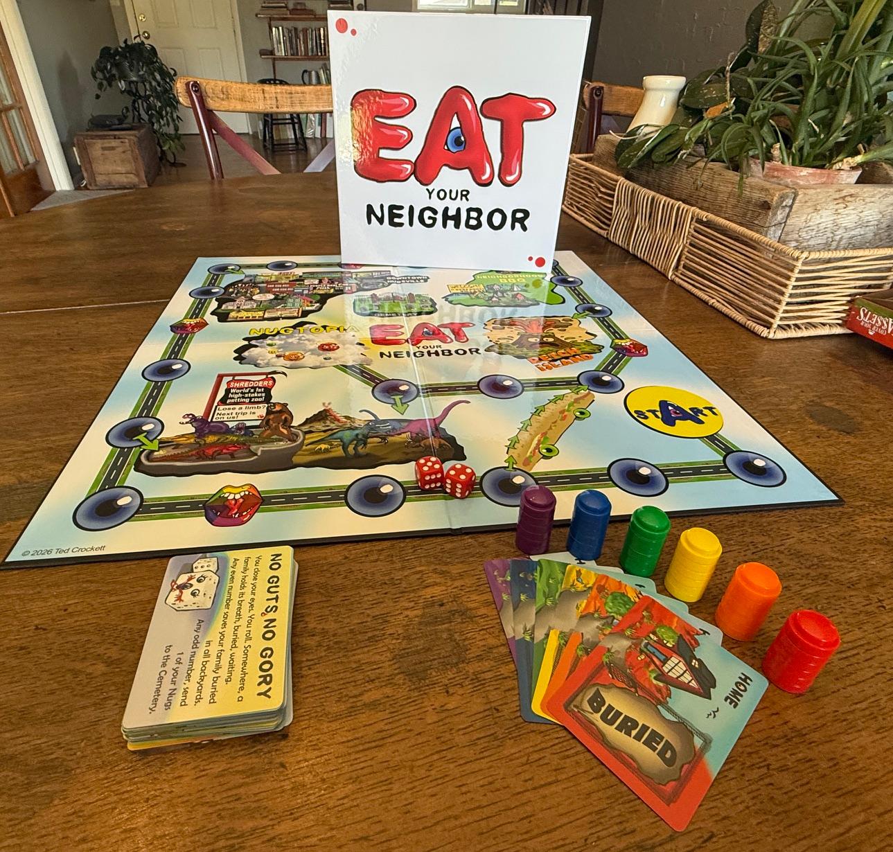The Eat Your Neighbor game set up on a table, with the game board, box, cards, and Nug pieces